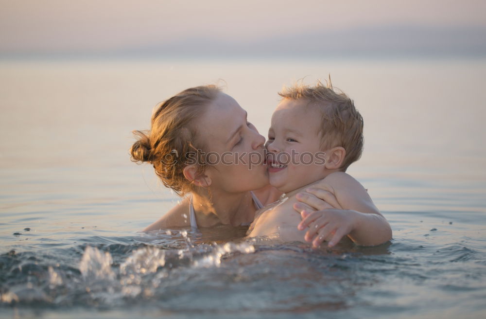 Similar – Image, Stock Photo Mother kissing her young child while bathing in the sea waters during sunset