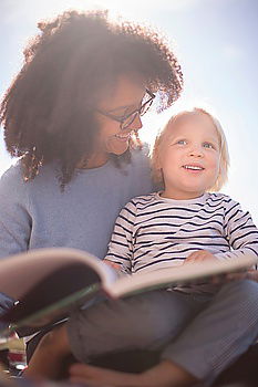 Similar – Mom reading a book her little daughter