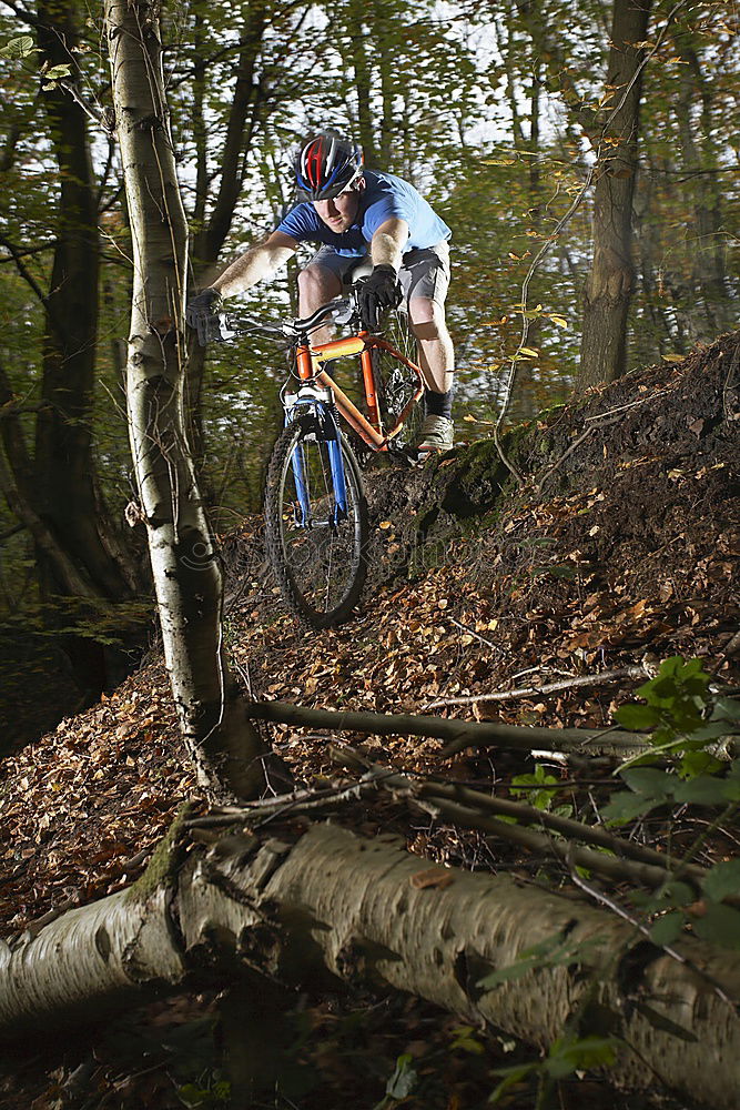 Similar – Biker in Jeans und kariertem Hemd springt mit dem Fahrrad die MTB-Strecke hinunter