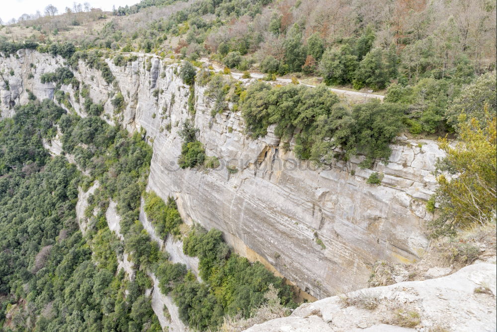 Similar – A detail of a cliff with a waterfall framed by the leaves of some trees