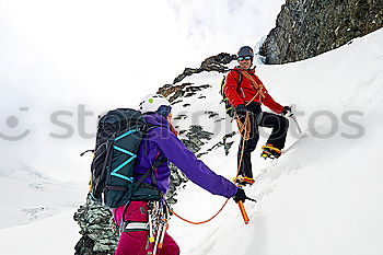 Similar – Climber helps another climber to reach the top of a mountain