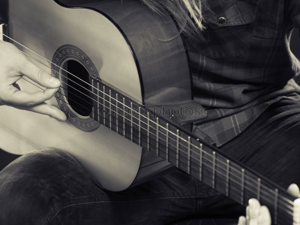 Similar – man playing spanish guitar and singing while recording it with a microphone