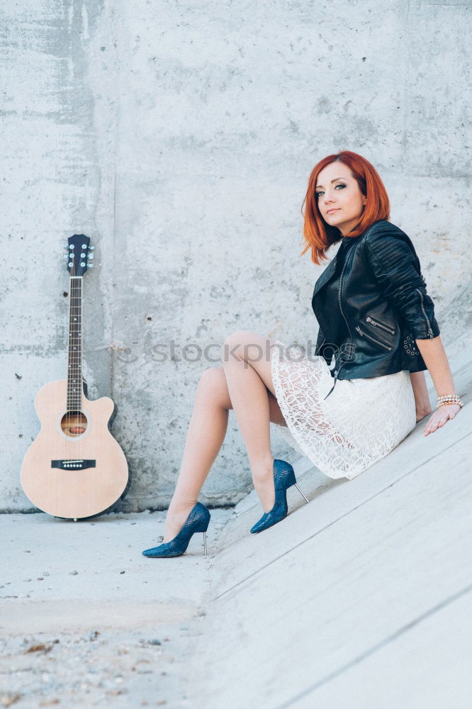 Pensive woman sitting near guitar on floor