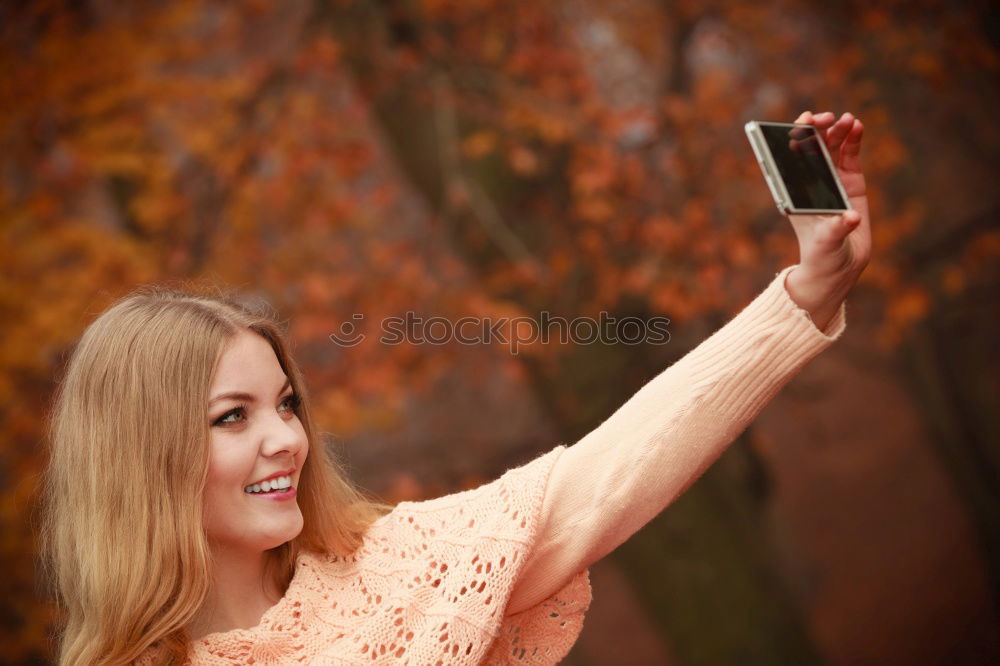 Beautiful Smiling Woman in red coat with mobile phone in hands, smartphone, urban scene