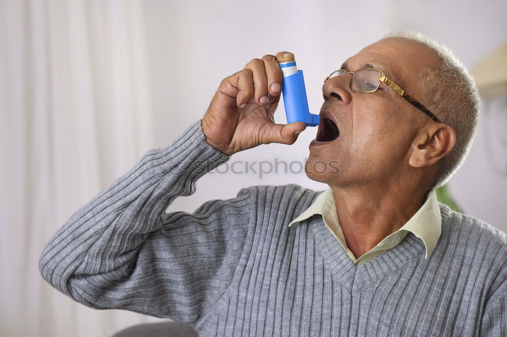 Senior man using medical equipment for inhalation with respiratory mask, nebulizer