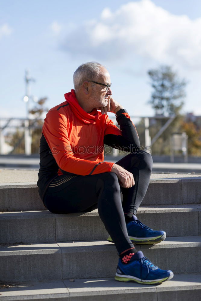 Senior runner man sitting after jogging in a park