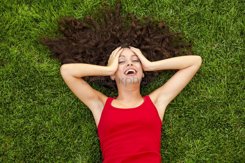 young cheerful woman lying down on the grass