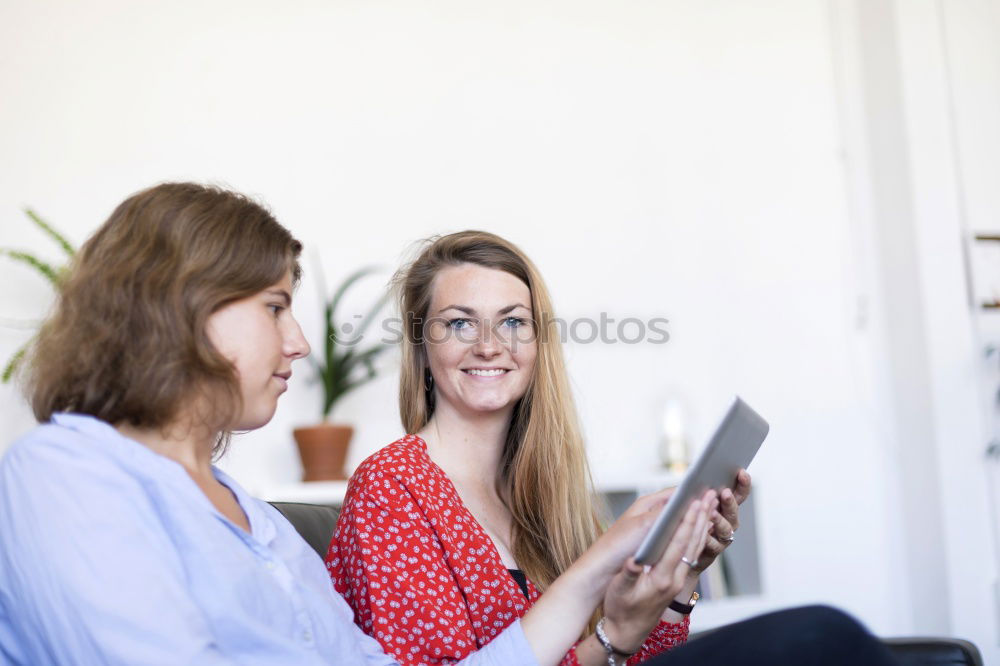 Similar – Image, Stock Photo Two friends talking and laughing on a sofa in the living room at home