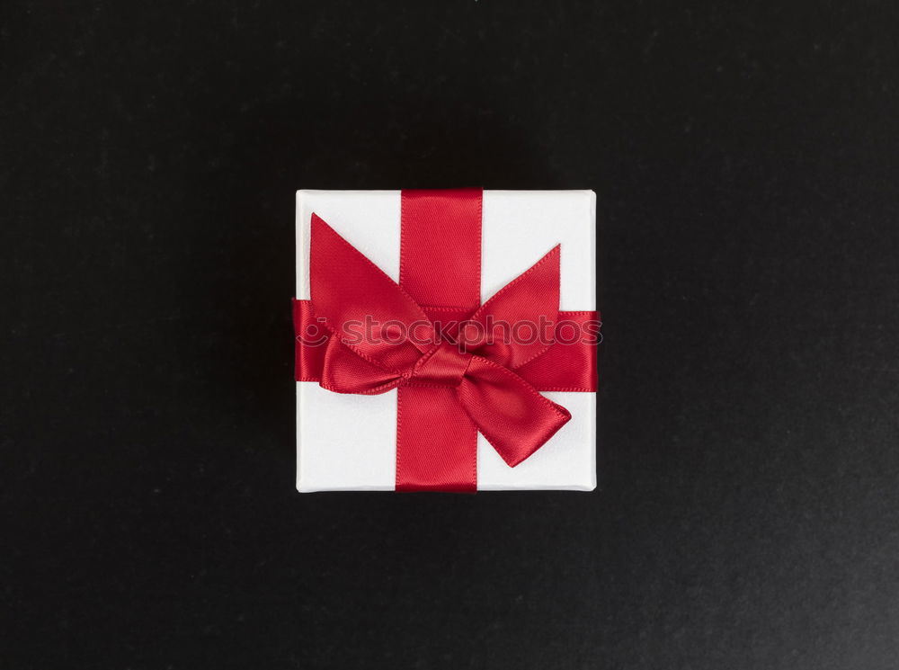 Similar – Packed gift with a red ribbon on a white plate