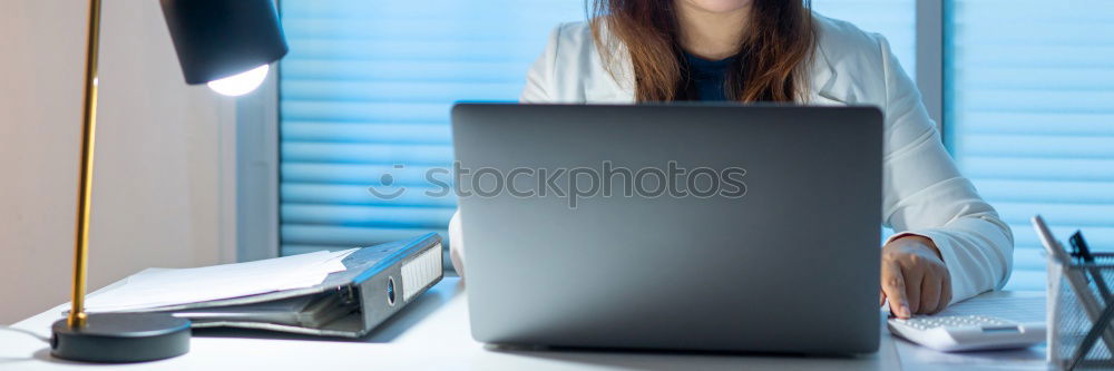 Concentrated young lady using laptop and sitting at table