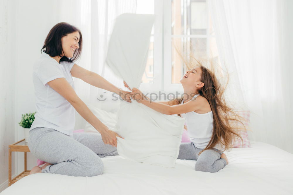 happy mother and child son fooling and playing in bed