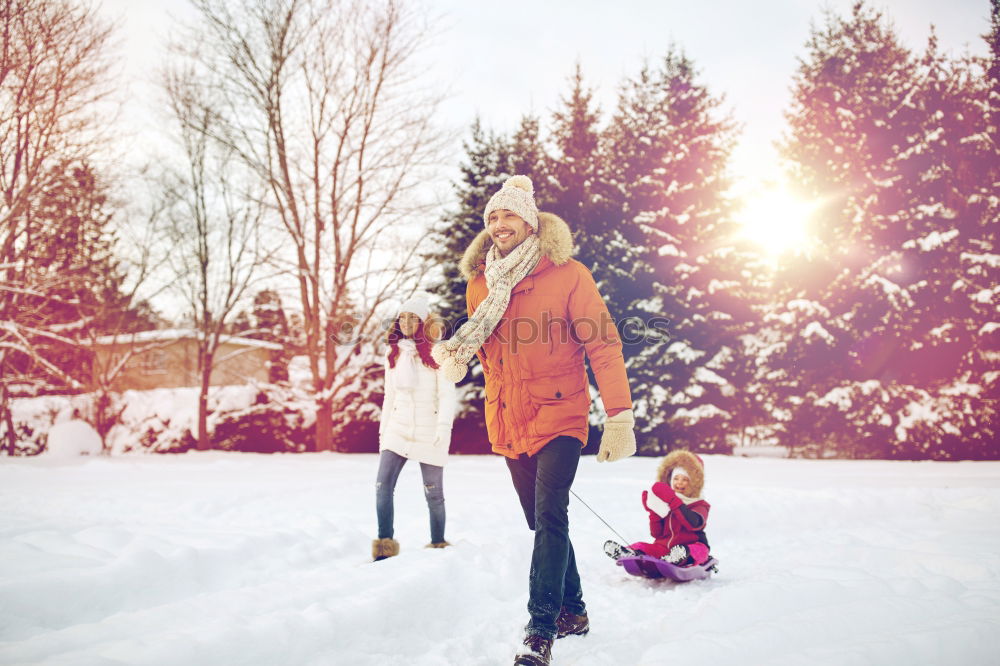 Teenage girl pulling sled with her little sister through forest