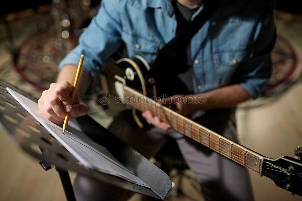 man playing spanish guitar and singing while recording it with a microphone