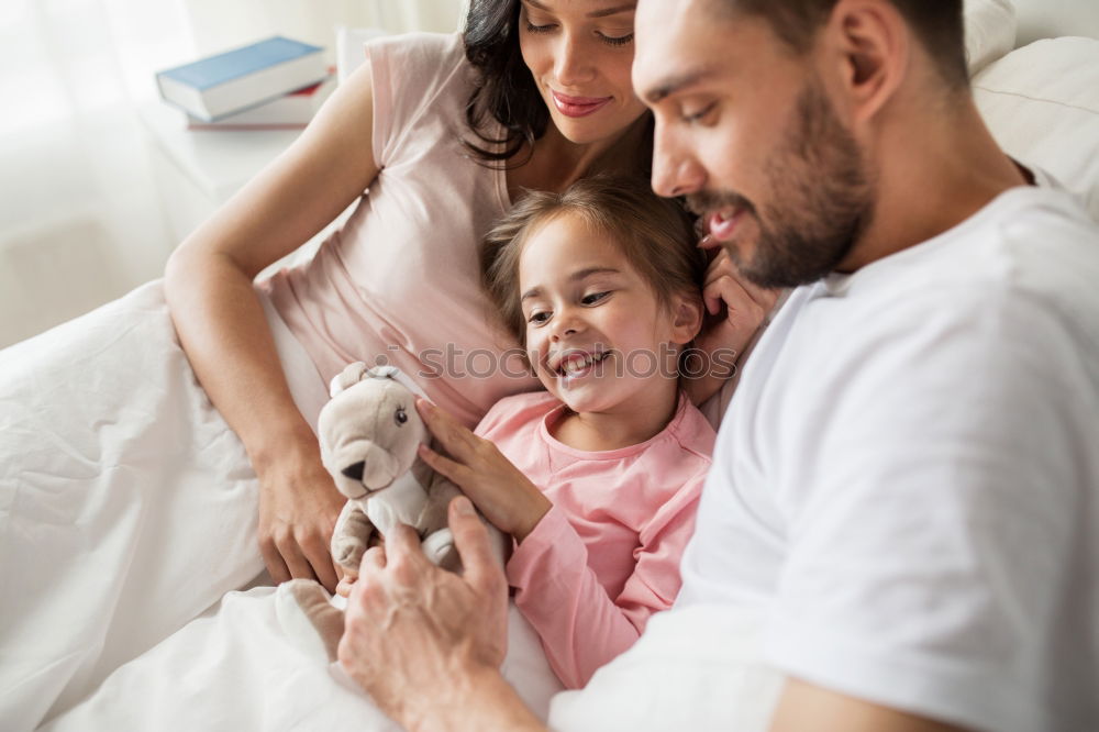 Couple relaxed at home in bed with their little daughter and the dog