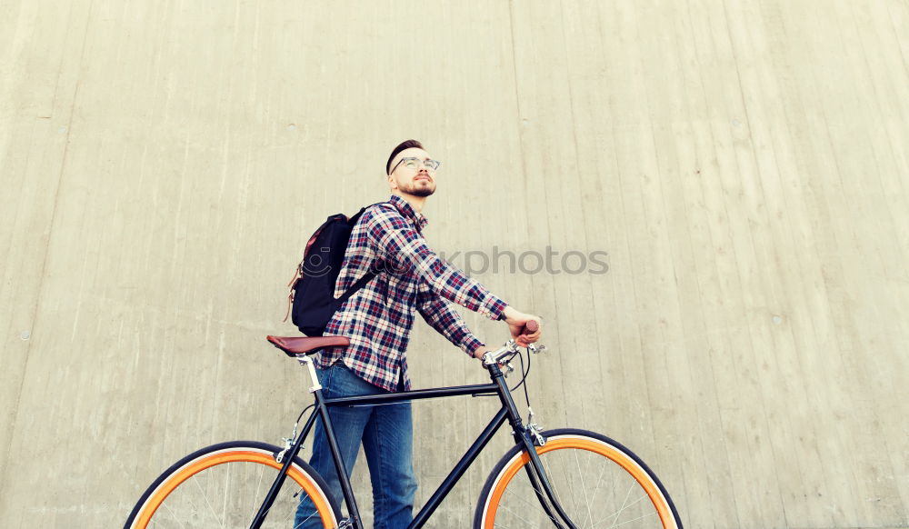 Young man riding bicycle and listening to music in headphones on city street