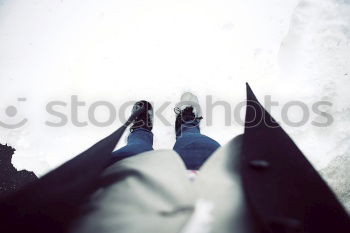 Image, Stock Photo A woman is standing in the snow.  Next to her two empty footprints. She wears black and white striped stockings and purple boots.