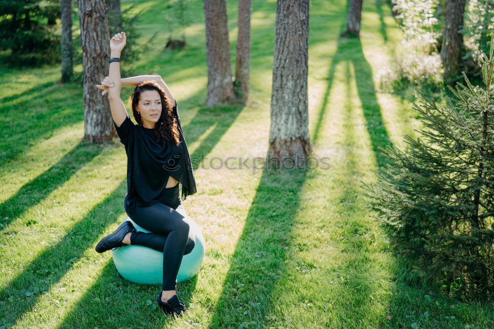 Winter ideas. Beautiful young girl stretching her finger upwards while snowing on a green meadow.