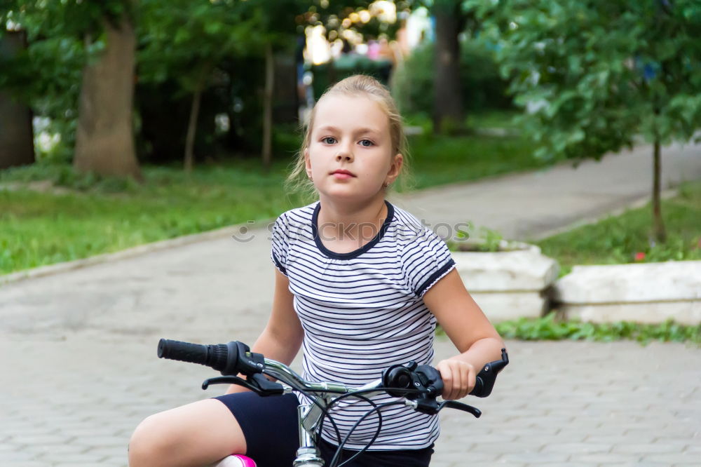 Cute girl driving bicycle in summer