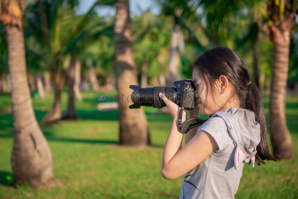 Similar – Smiling young woman using a camera to take photo at the park.