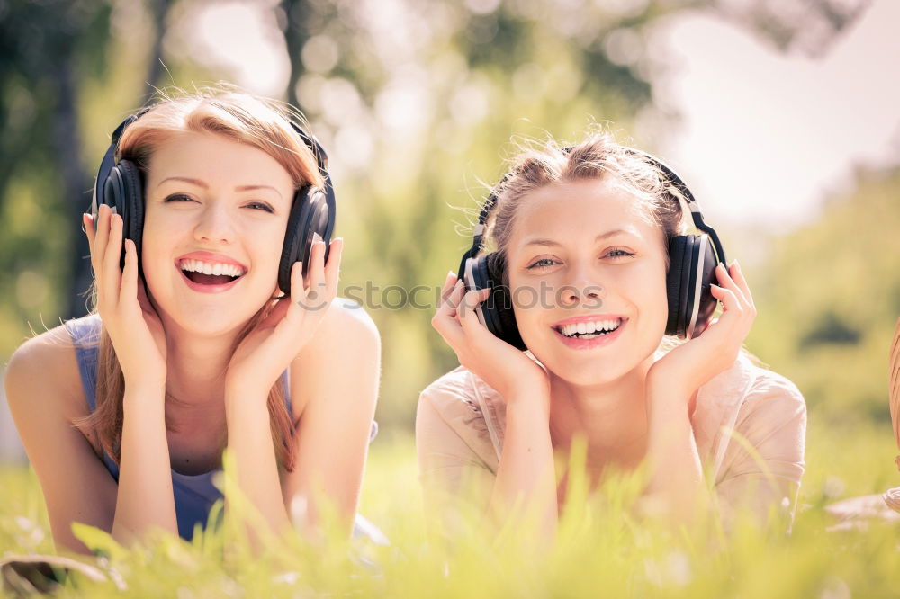 Similar – Two happy teenage girls lying on the grass sharing headphones to listen to music