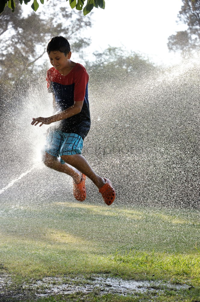 Similar – Little boy jumps into a puddle that makes the water run high