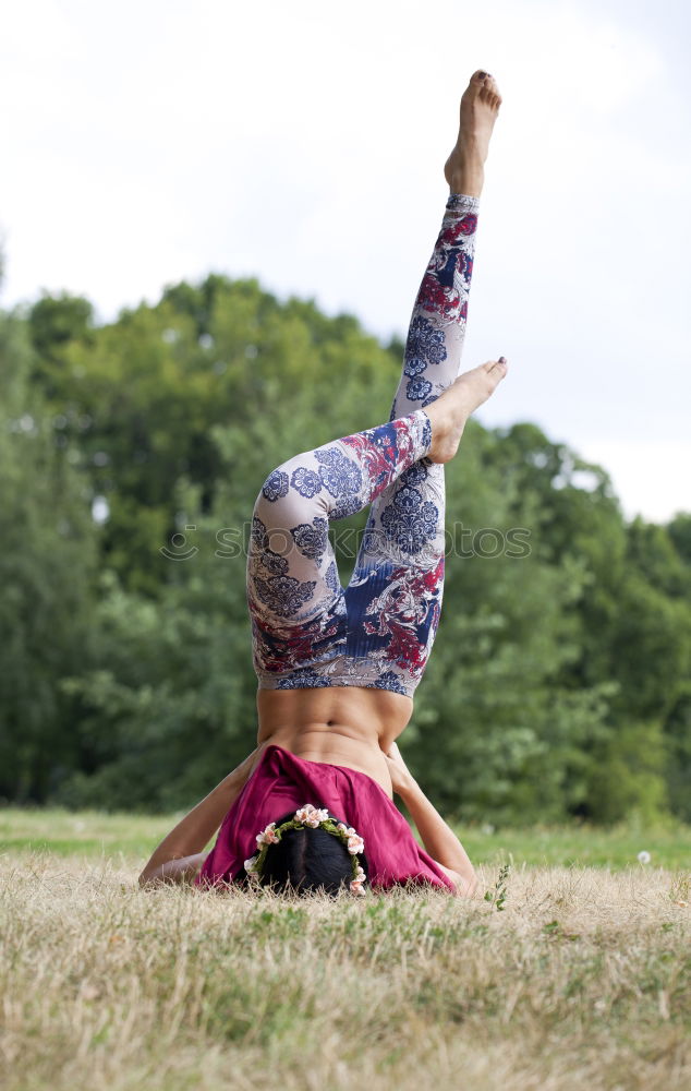 Similar – Agile young woman doing a handstand outdoors in the countryside balancing on her hands with her legs bent in opposite directions