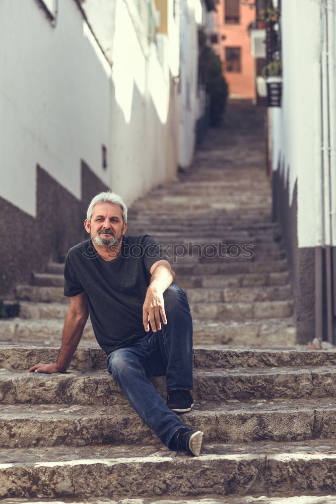 Portrait of a mature man sitting on steps in the street