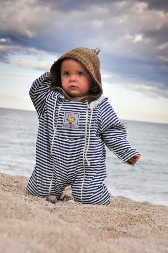 little girl stands on beach in a special swimsuit for children who can not swim. child in swimsuit, which he kept afloat