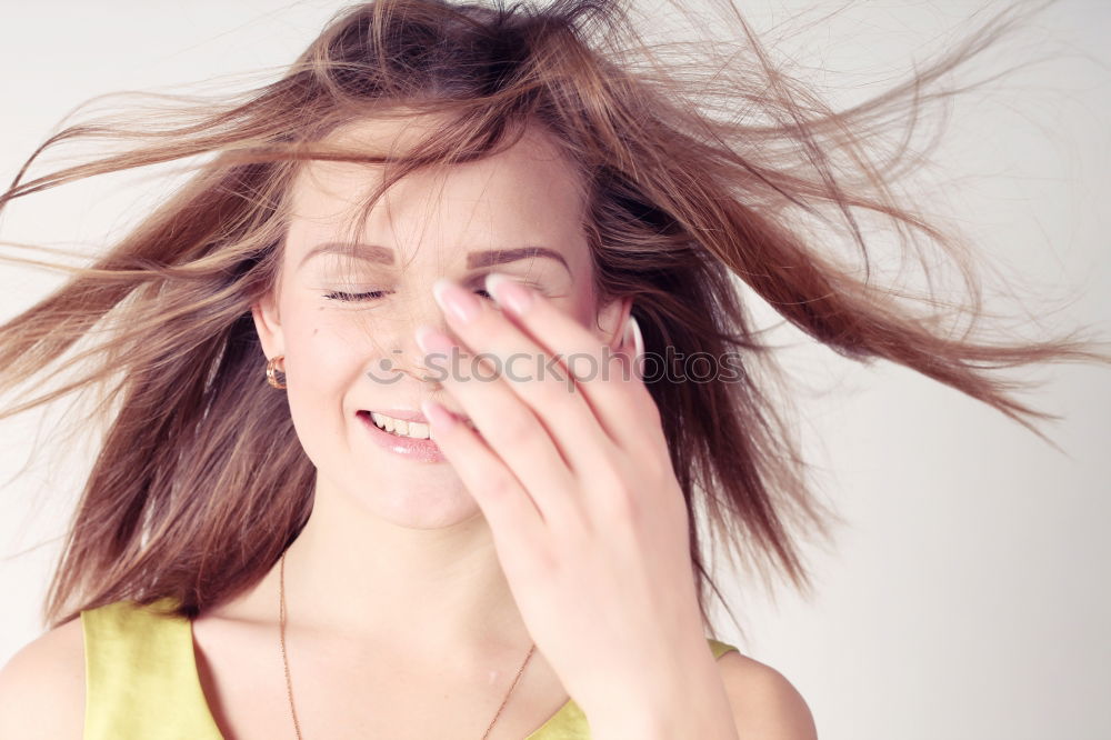 Portrait of a dark blond, long-haired woman looking into the camera through the hair on her face