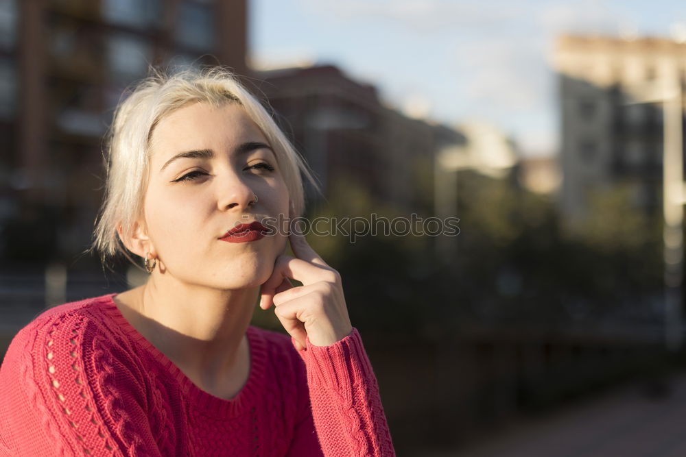 Portrait of a young blonde woman gesturing in the street wearing a red sweeter