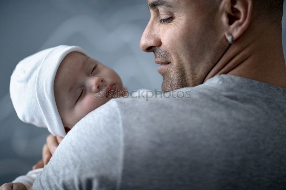 Image, Stock Photo Couple embracing and looking to their newborn over dark background