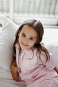 Similar – happy child girl sitting on bed and hugs pillow