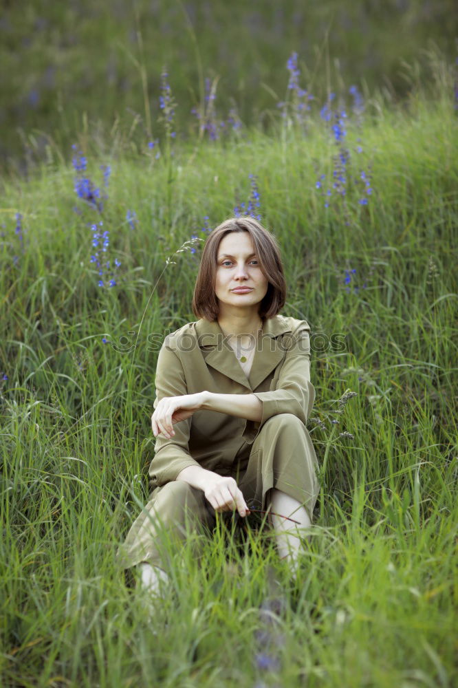 Similar – side portrait of young woman in summer dress sitting barefoot between bushes in nature