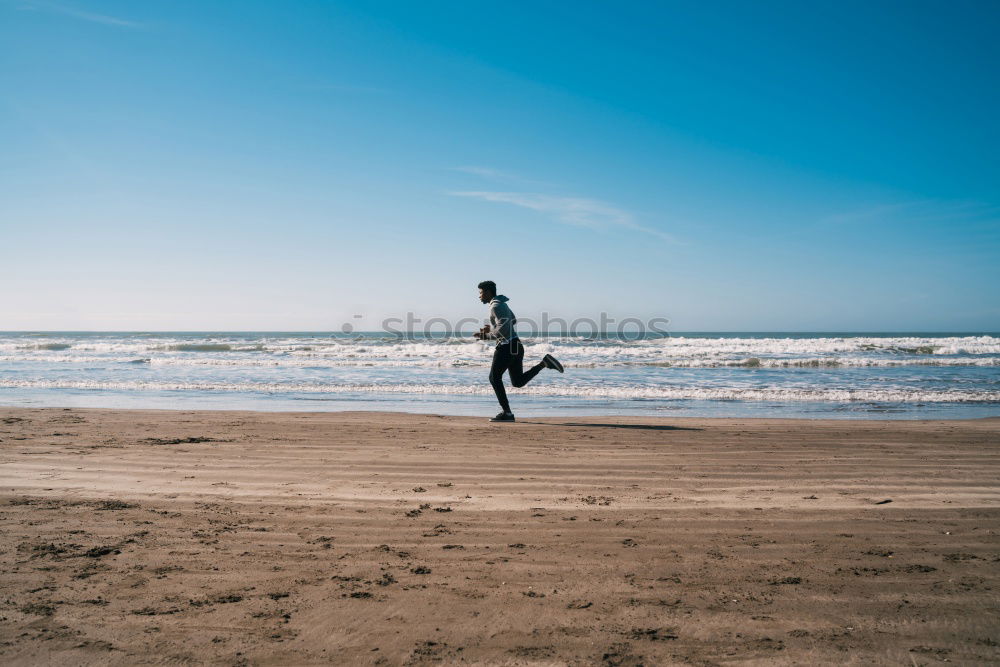 Similar – Naked man runs liberated on the empty beach towards the undulating sea