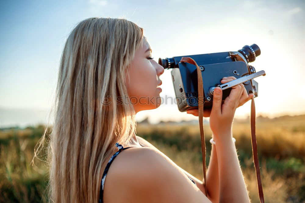 Similar – Smiling young woman using a camera to take photo at the park.