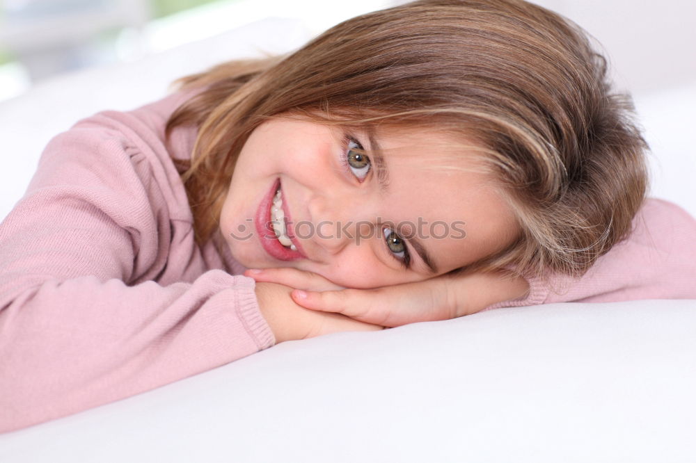 Similar – happy child girl sitting on bed and hugs pillow