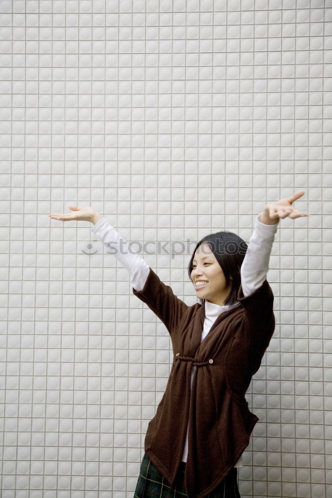 elegantly dressed lady with black coat, red hat, red scarf and red pumps is dancing on a large square with concrete and patterned floor