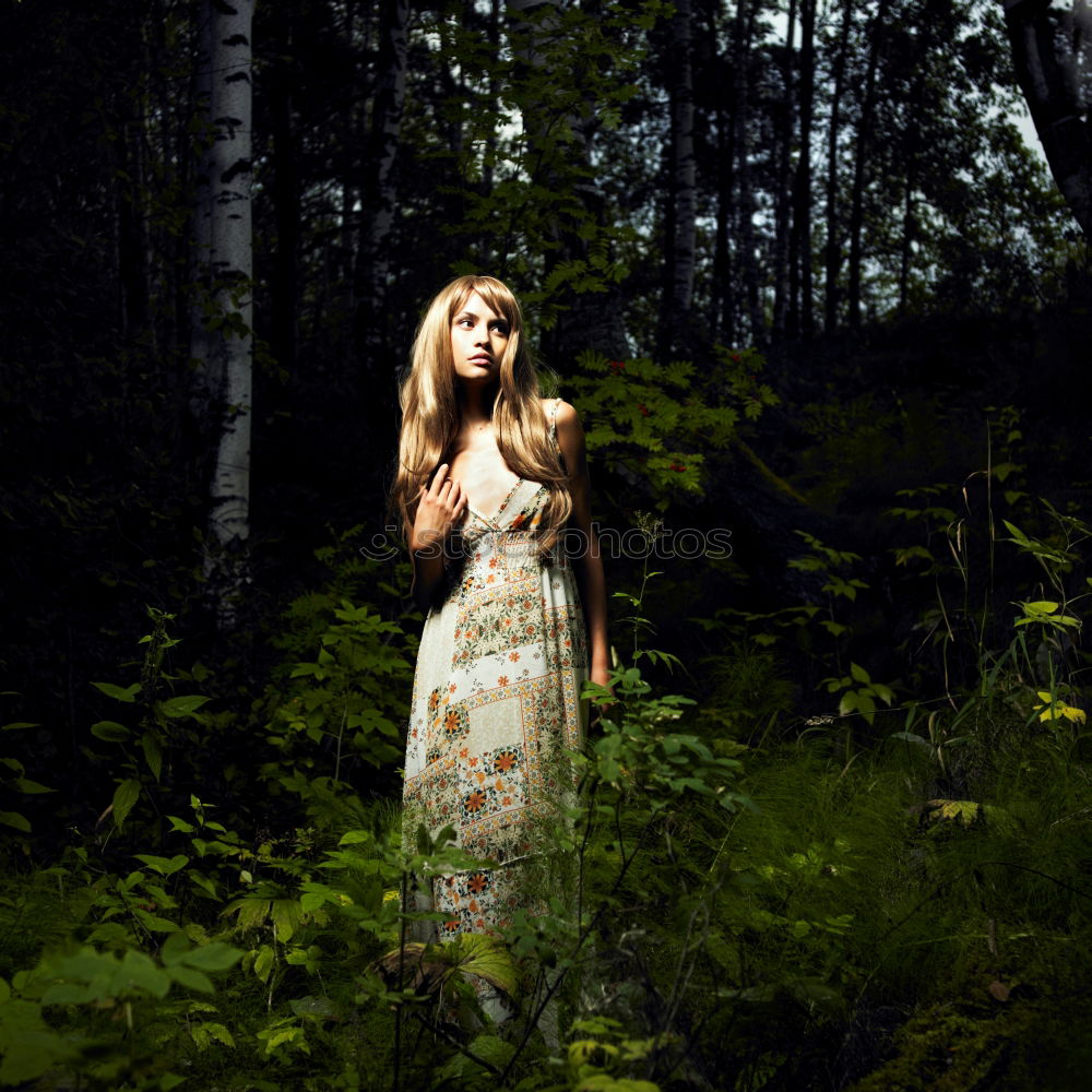 Similar – Young beautiful tall woman sitting barefoot on the ground in the forest looking at the camera against the sun