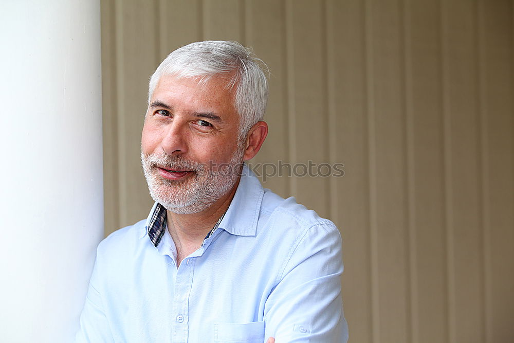 Portrait of a senior citizen with short grey hair and three-day beard in front of a blue-grey sky