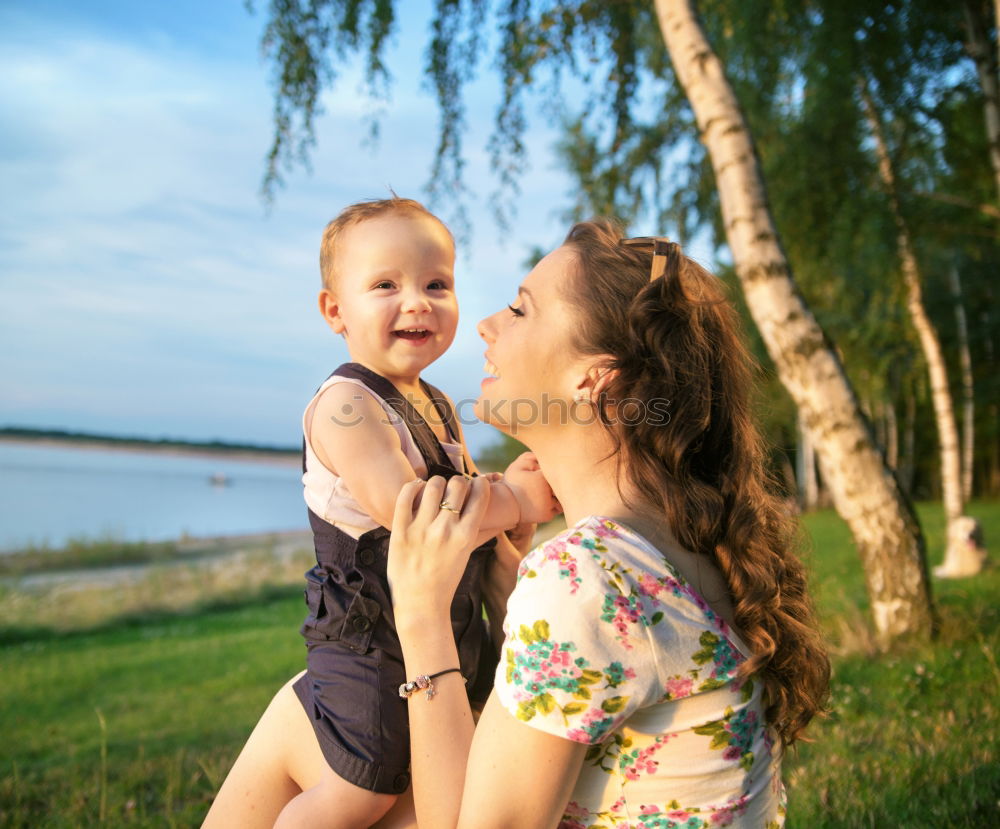 Similar – Mother holding kid on hands in park