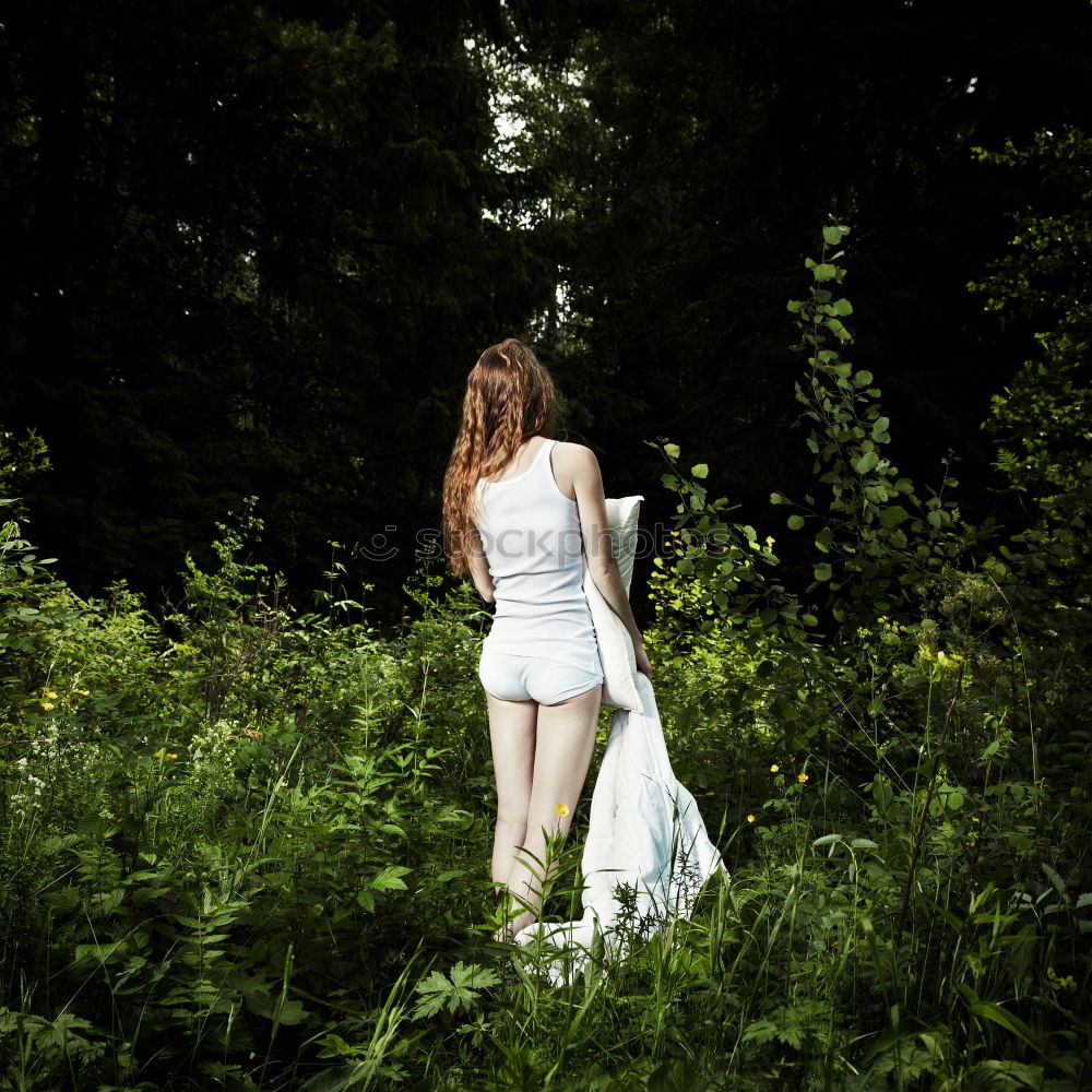 Similar – Young beautiful tall woman sitting barefoot on the ground in the forest looking at the camera against the sun