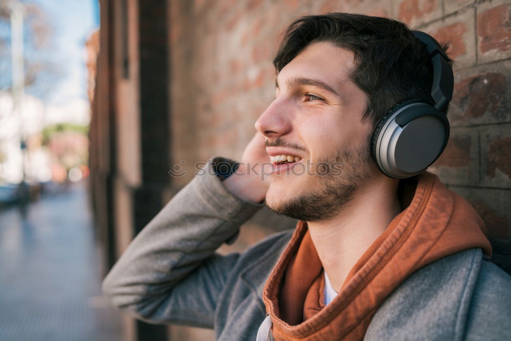 Image, Stock Photo Young man waiting listening music and using mobile phone at the airport with a suitcase.