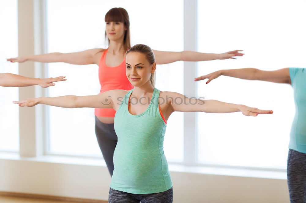 Group of young sporty attractive women in yoga studio, practicing yoga lesson with instructor, standing, stretching and relaxing after workout . Healthy active lifestyle, working out indoors in gym