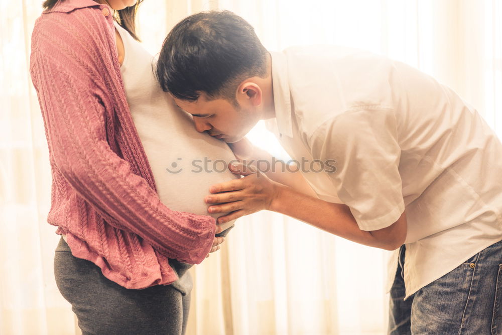 Similar – Image, Stock Photo Happy man listening and touching his pregnant wife tummy on the sofa at home