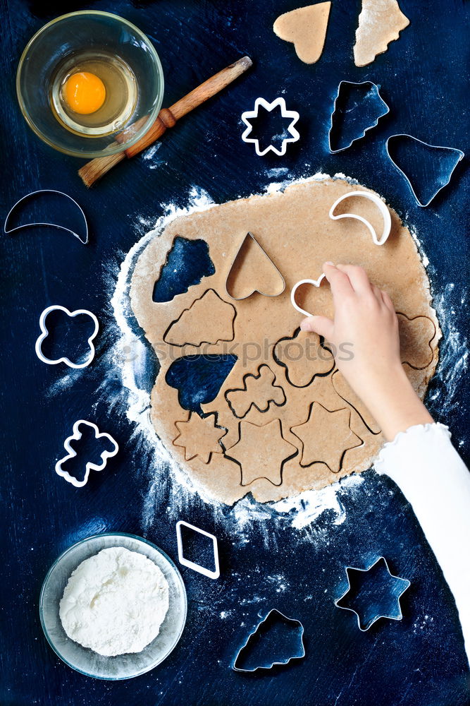 Girl cutting out the Christmas symbols in the dough