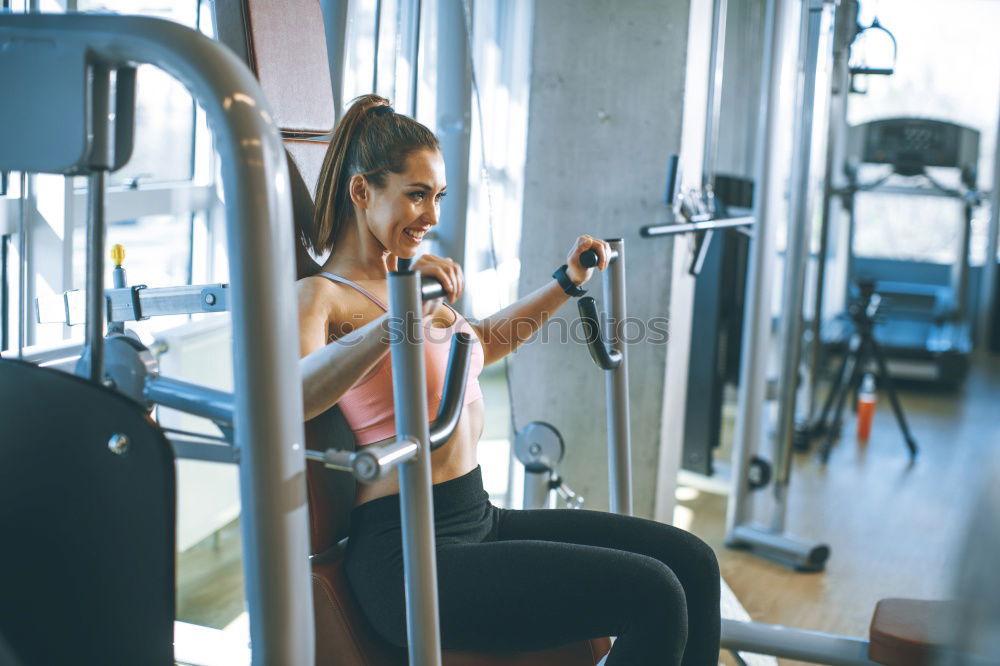 Sporty woman sitting with dumbbells and smartphone in gym floor