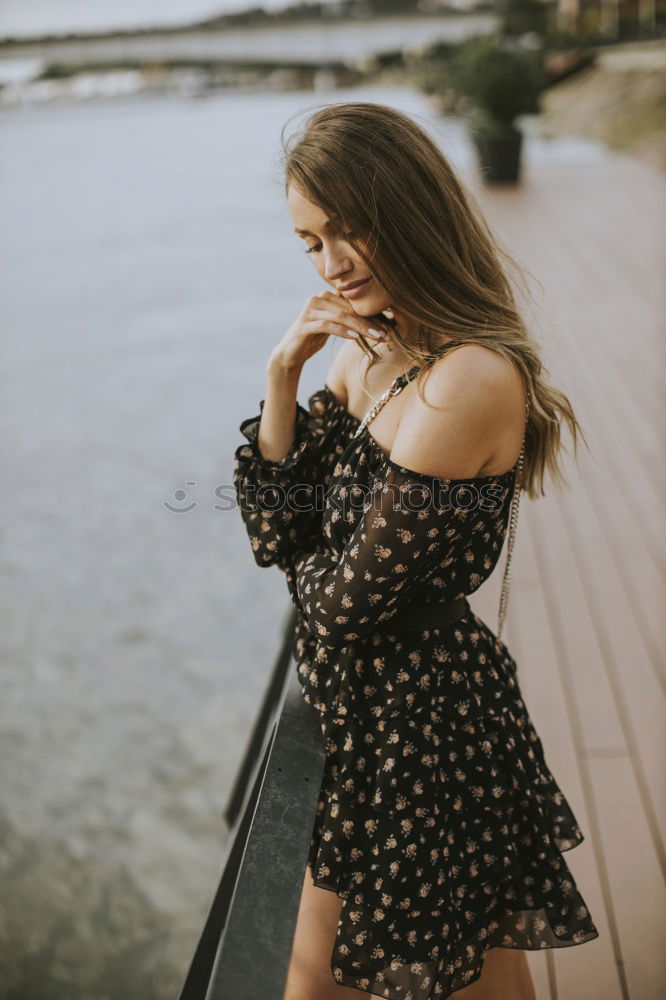 Similar – Brunette woman leaning on handrail at river