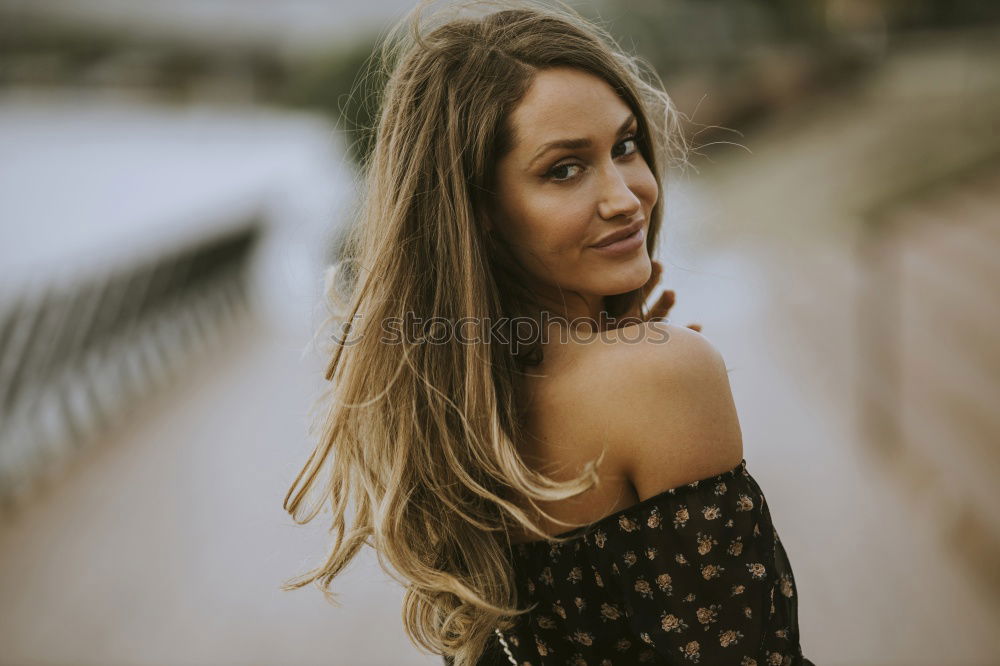 Brunette woman leaning on handrail at river