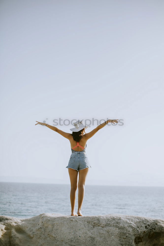 Similar – Girl with arms raised standing on the cliff