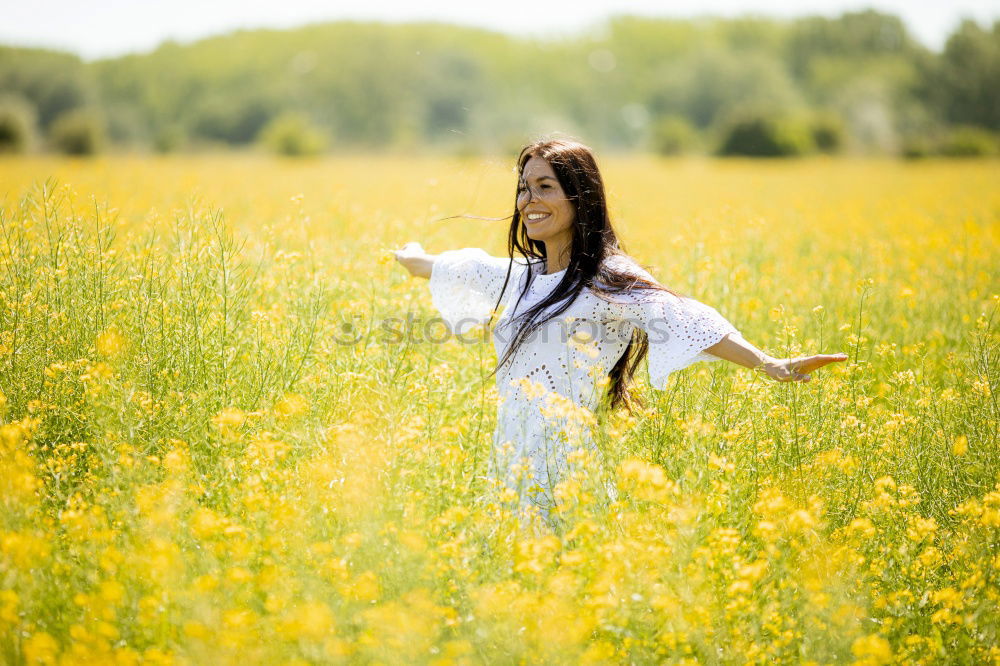 Similar – Image, Stock Photo Beautiful young woman enjoying the warm sun in the nature. Attractive girl is in yellow green meadow full of flowers. With head up and eyes closed she is happy about spring or summer.